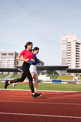 Fototapeta premium Young fitness woman runner jogging excercise in the morning on city stadium track in the city. Female athlete excercise in the city stadium to keep body fitness. Stock photo.