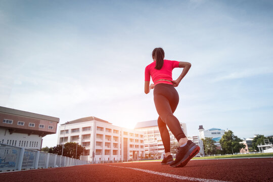 A young fitness woman runner jogging excercise in the morning on city stadium track in the city. Female athlete excercise in the city stadium to keep body fitness. Health and recreation stock photo.