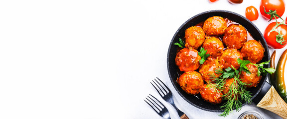 Meatballs with tomato sauce and spices in frying pan on white kitchen table background. Panoramic banner with copy space