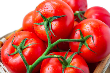 Fresh organic tomatoes with water drops in a basket isolated on white. Close up.