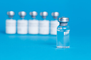 Closeup vaccine bottle on blue isolated background. Lack of coronovirus vaccine.