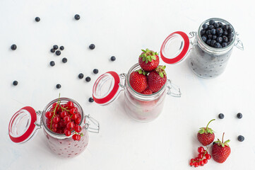 Jars of strawberries with red currants and blueberries on a white background. View from above.