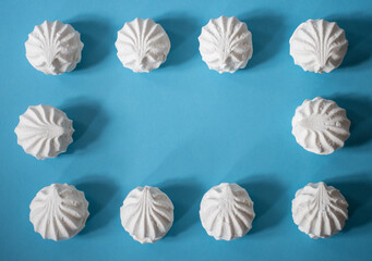 Frame on a blue background of ten white marshmallows: delicious sweet background, space for text