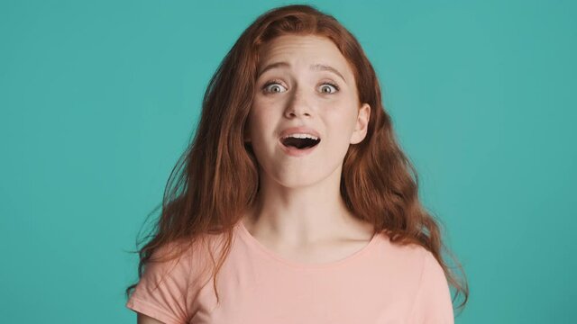 Portrait of pretty excited redhead girl surprisingly looking in camera over colorful background. Wow expression