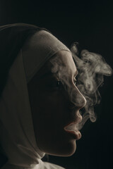 The beautiful nun blows smoke from her mouth.