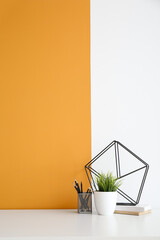 Fototapeta na wymiar Stylish workplace with houseplant and stationery near color wall