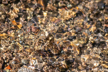 Silky ripples in water of a crystal clear water creek as idyllic natural background with high angle view shows zen meditation and little waves in a healthy mountain spring with a clear floating stream