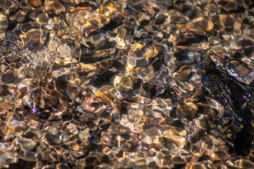 Silky ripples in water of a crystal clear water creek as idyllic natural background with high angle view shows zen meditation and little waves in a healthy mountain spring with a clear floating stream