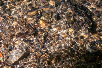 Silky ripples in water of a crystal clear water creek as idyllic natural background with high angle view shows zen meditation and little waves in a healthy mountain spring with a clear floating stream