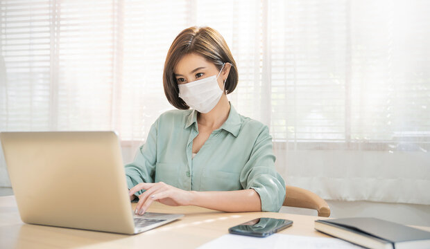 Portrait of sme business asian woman in wears medical protective mask working from home at computer desktop. Self-isolation quarantine, new normal. Coronavirus outbreak, flu covid epidemic concept