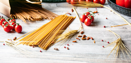 Italienisch kochen Vollkorn Pasta roh und ungekocht mit frischen Tomaten auf einen Holztisch
