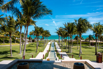 Obraz premium ocean skyline at tropical resort with palm trees grass and long pool