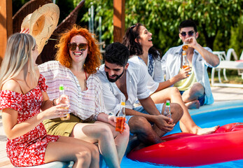 Group of young people having fun at summer vacation and enjoying a poolside party with drinks.