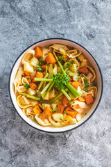 plant-based food, vegan ravioli pasta with vegetable broth topped with pumpkin and sweet potato cubes and celeri sticks
