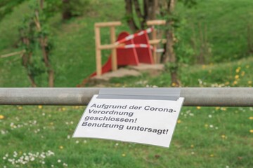 Corona virus quarantine lockdown prohibit playground slide. Covid-19 safety prevention. Closure prohibition sign. German text mean closed because of coronavirus restriction regulation! Keep off! - 366002549
