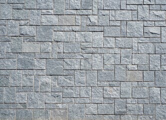 Stone wall with gray stone tiles of different dimensions and shape arranged geometrically. Background and texture