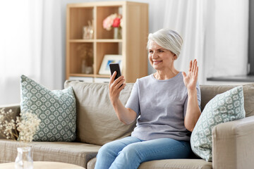 technology, people and communication concept - happy smiling senior woman with smartphone having video call at home