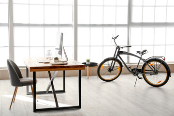 Stylish interior of room with workplace and bicycle