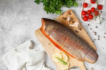 Smoked fish trout. Whole Smoked trout on the serving Board. Smoked trout lay on the light gray kitchen table. Smoked fish close-up. Top view with space for text