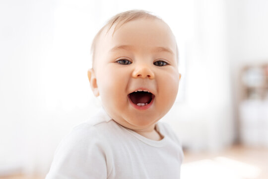 childhood and people concept - portrait of happy laughing little baby at home