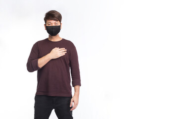 Asian man wearing a black face mask put a hand to heart, new normal greeting, social distancing, isolated on white background, COVID-19 concept.