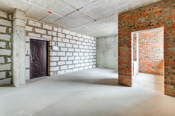The unfinished apartment room in a multistory residential building under construction with walls without finishing. The use of aerated concrete blocks for building indoor walls