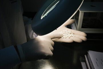 Hands of a scientist examining some white pills