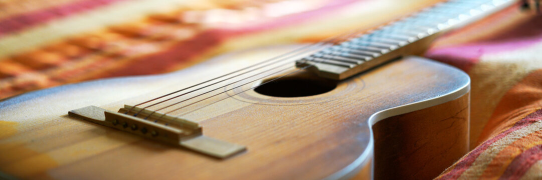 acoustic wooden guitar put on striped blanket close view
