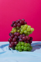 Stack of green and red grapes on a blue drapery