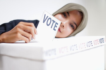 Young woman with nikab putting a ballot into the ballot box. Election Concept