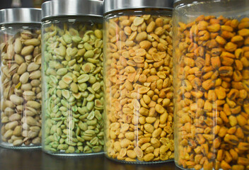Corn, peanuts, pistachios in glass jars on the counter