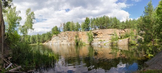 Obraz premium Panorama of scenic forest lake with rocky shores in summer