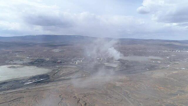Aerial view of copper plant in Karabash city. Around the contaminated area. Smoke comes out of the chimney and flies into the camera. Cars drive on the road. Russia, Chelyabinsk region