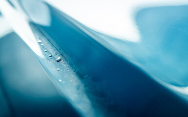 Closeup shiny blue car texture with water drops. Blue car is washing with water. Auto care...