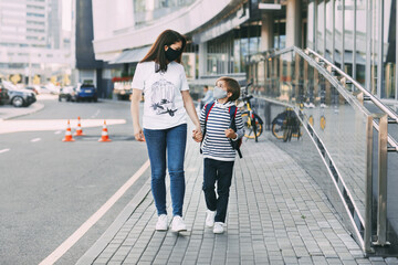 A mother and a boy in a mask on their way to school or kindergarten. A mother walks her son with a backpack to school. Social distance. Space for text
