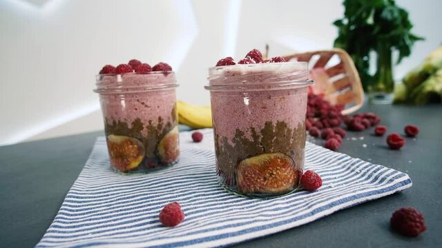 Smoothie glass decorated with coconut and raspberries.Served glass with healthy smoothie with fags, raspberries, bananas and coconut. Side view.