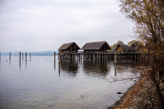 Bootsh&auml;user auf Pf&auml;hlen an einem See in den Alpen, im Hintergrund bedeckter Himmel 