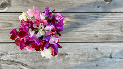 Bouquet sweet peas, flat lay, minimalist design, wooden grungy background. Photography from above. Backdrop, banner, perfect for social media, greeting or invitation cards, copy space, place for text.