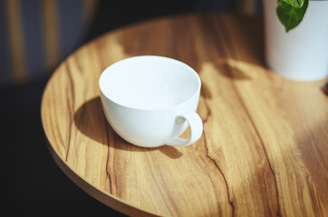 Empty white cup on table in cafe. Morning light falls from the window.Coffee break.Blurred image,selective focus