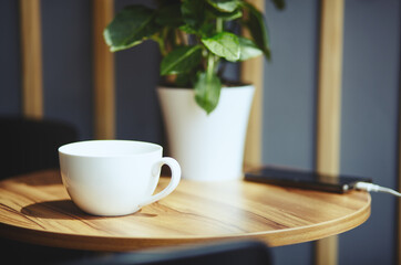 Empty white cup and smart phone on table in cafe. Morning light falls from the window.Coffee break.Blurred image,selective focus