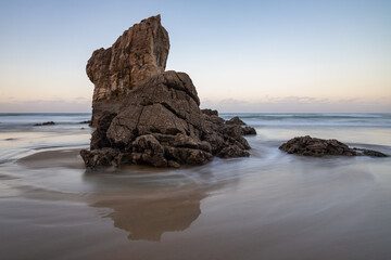 Fototapeta na wymiar Corriente de agua rodeando roca en la playa