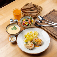 Whole lunch in a restaurant: summer salad, cream soup, meat with potato and fruit drink