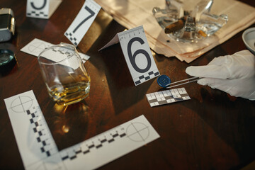 Detective with tweezers takes button, evidence