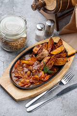 Meat and potato ragout, baked and served in a cast-iron skillet on grey concrete background