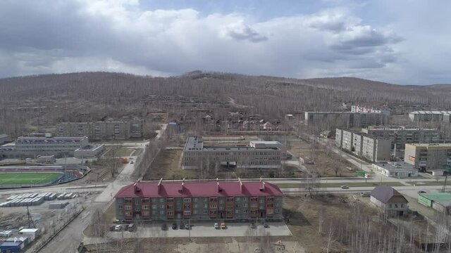 Aerial view of Karabash city with three-story and five-story houses. Spring, trees without leaves. At the background the Ural mountains. Russia, Chelyabinsk region
