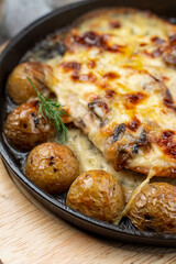 Mouthwatering pub dish in cast iron: baked baby potato with poultry and cheese crust