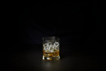 Glass of whiskey with ice on a dark background