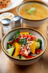 Summer vegetable salad with bell pepper, cucumbers and tomatoes in a bowl as a part of lunch