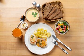 Directly above studio photo of set lunch: meat roulade with boiled egg, potato, soup and salad