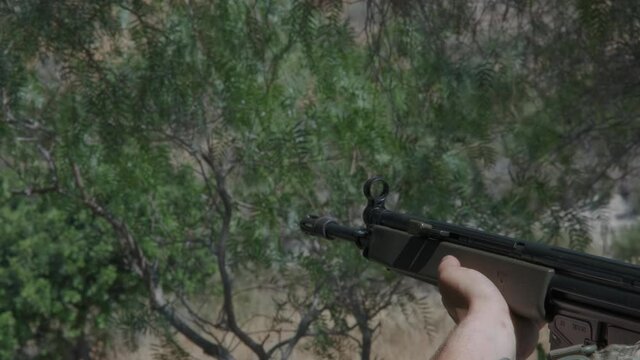 Close-up of a G3 rifle being fired at an unknown target in the woods.